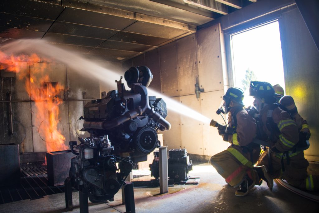 Fire Science students practice putting a fire out in the burn building