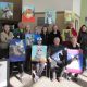 Students from CCC art class pose with paintings of animals from the local animal shelter