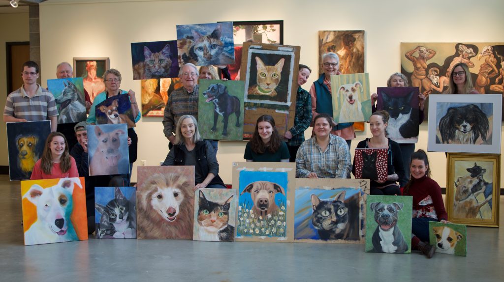 Students show off their paintings of local shelter cats and dogs that will be sold for a fundraiser for Clatsop Animal Assistance