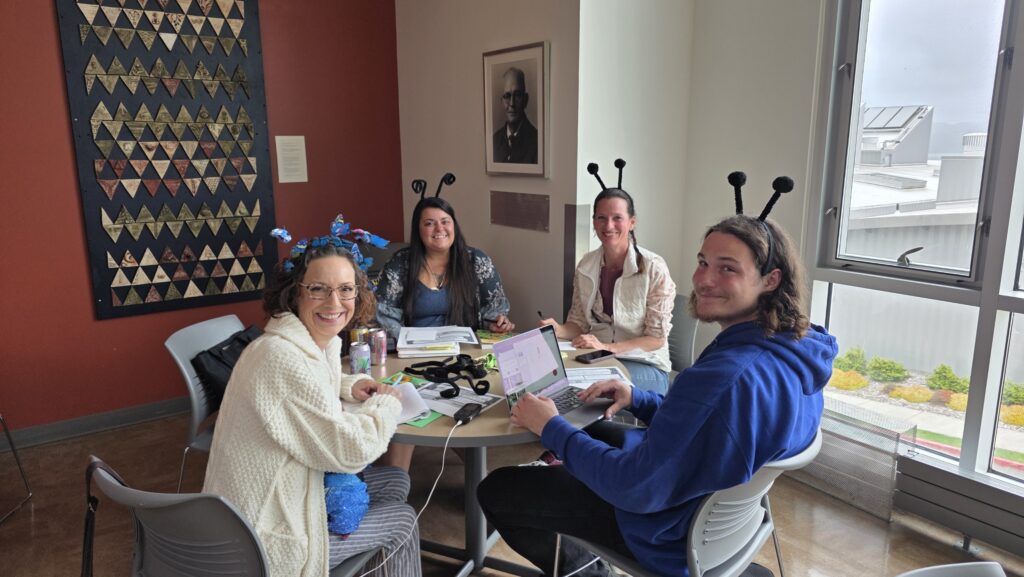 4 members of the Natural Explorations club sit at a table at a meeting