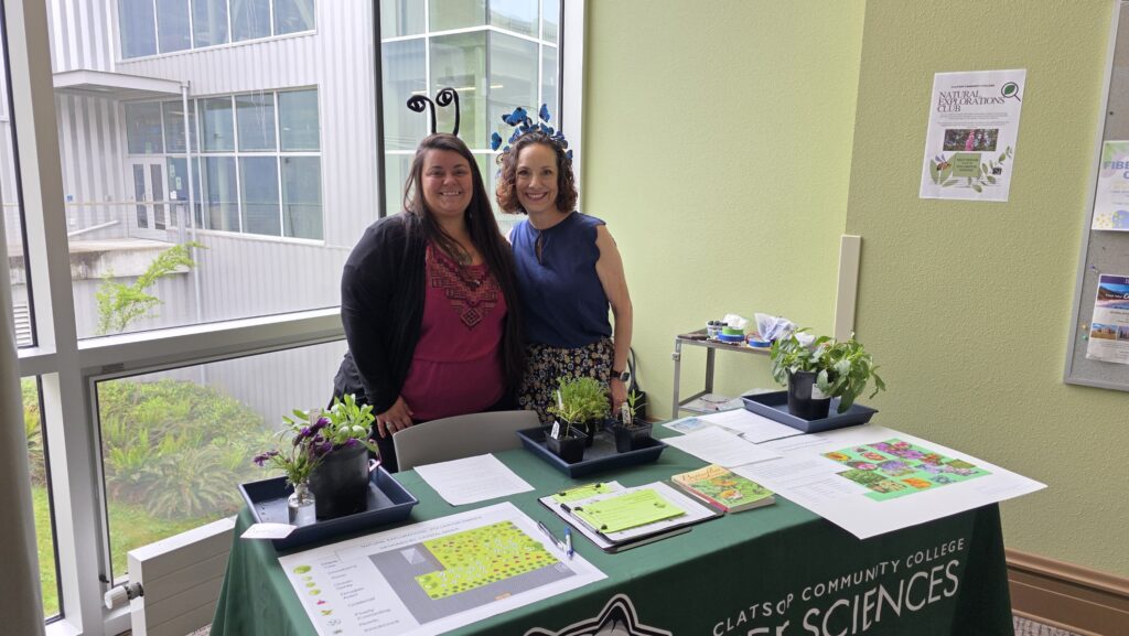 Crystal and Therese at a table with the designs for the layout of the pollinator garden