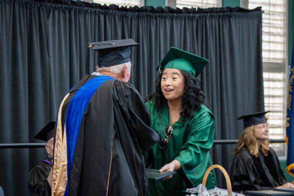 Argie Mendez-Alvarez shakes hands with the Board of Education Chair while receiving her diploma.