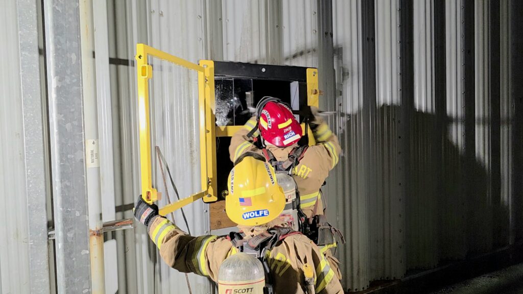 firefighter breaks through the window prop to enter the structure.