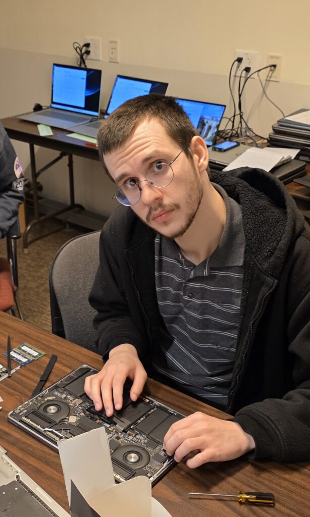 Work-study student Daniel works on a water-damaged laptop.