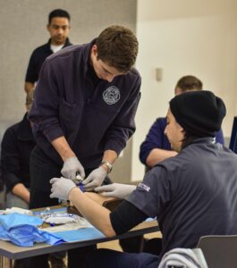 Students in an EMT class work on hands-on skills