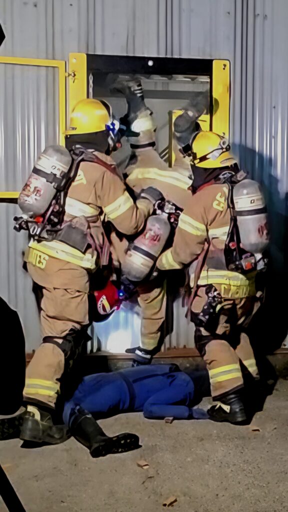 Firefighters finish their drill by exiting the structure through a window prop