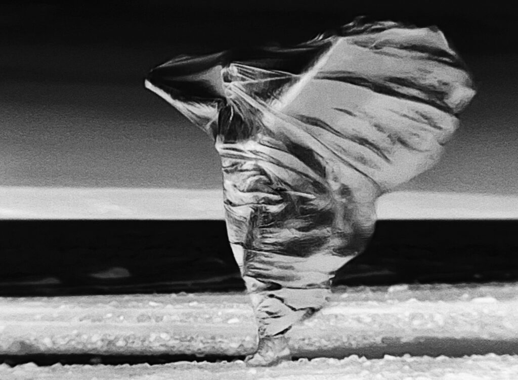 An infrared thermal video still as a digital photograph, depicting a woman' body beneath metallic fabric with their heat signatures visible.