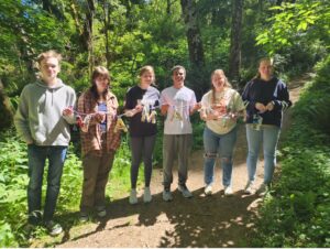 Clatsop Community College art students show off an art piece that will be part of the Shinrin-Yoku art hike