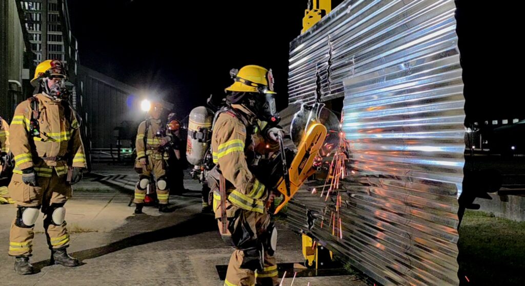 A Gearhart firefighter cuts through a garage door prop