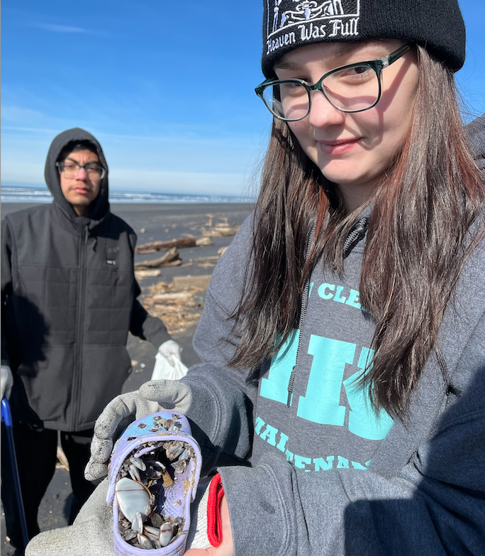 Nevaeh French holds a shoe with gooseneck barnacles during a CCC TRIO Beach clean up in February of 2023.