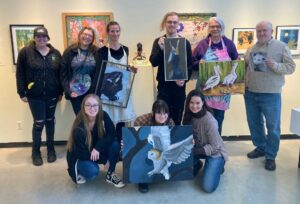 Painting students holding wildlife paintings